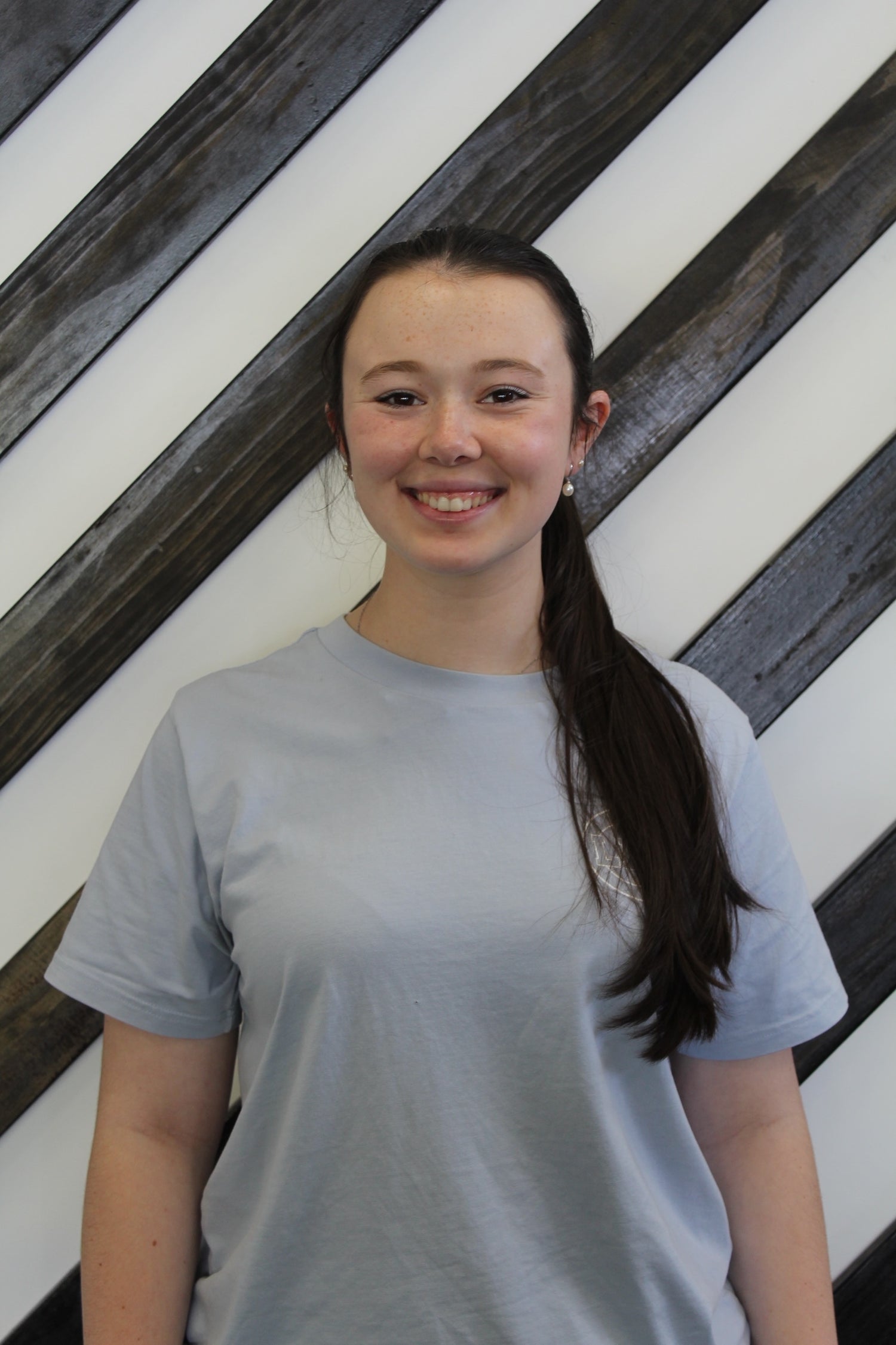 Audrey a physio at Leaton Performance standing behind a black and white striped wall.