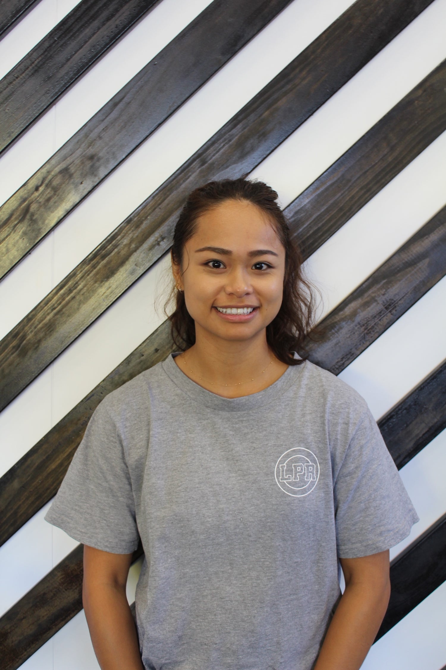 Eunice a physio at Leaton Performance standing behind a black and white striped wall.